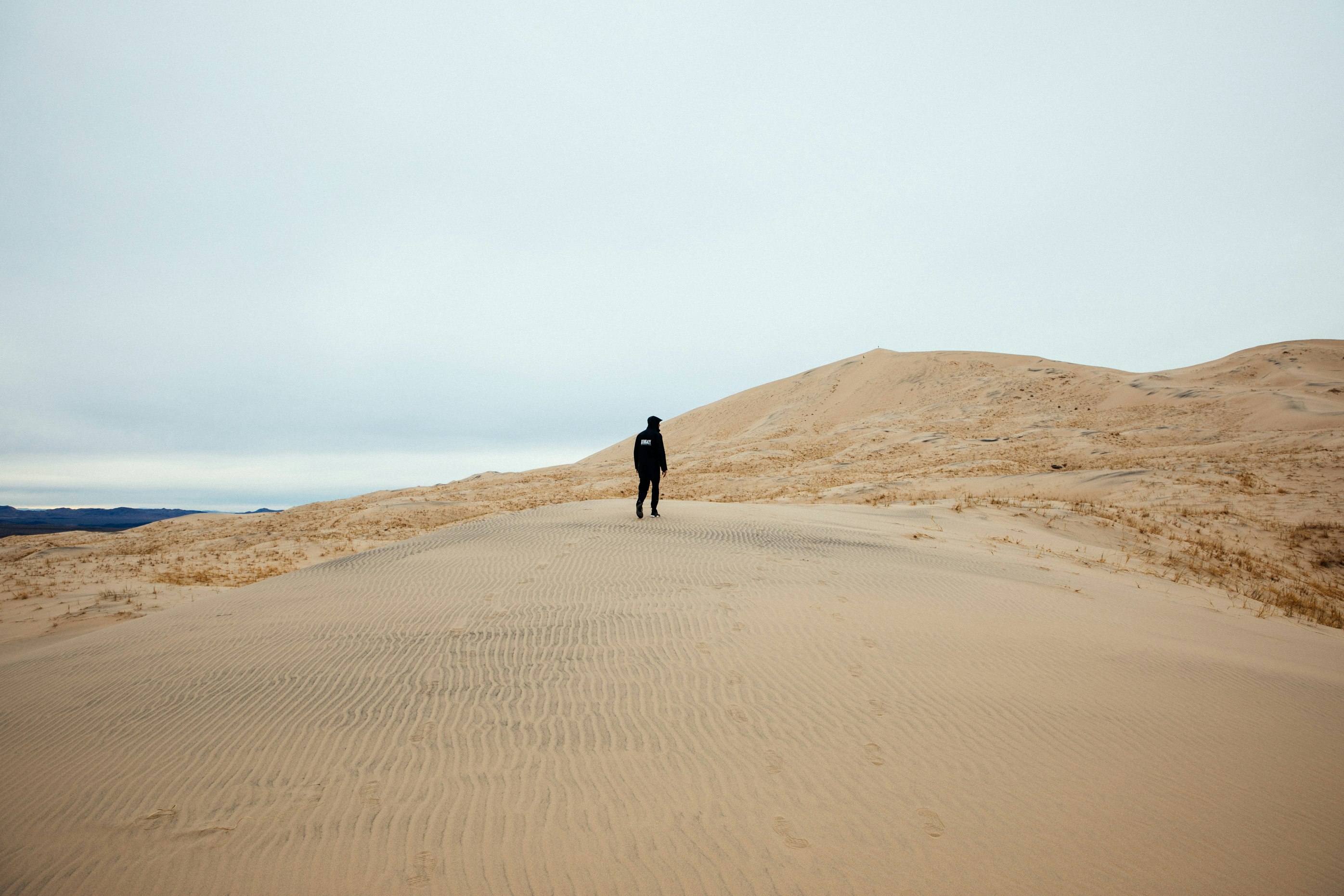 person walking in sand field during daytime